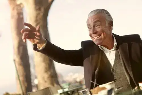 Cheerful mature man enjoying coffee and conversation at an outdoor café