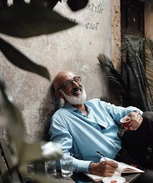 David, 59, laughing over coffee at an outdoor café