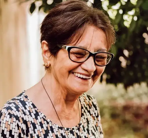 Margaret, 61, smiling outdoors in a garden
