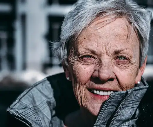 Susan, 58, smiling portrait in a city street